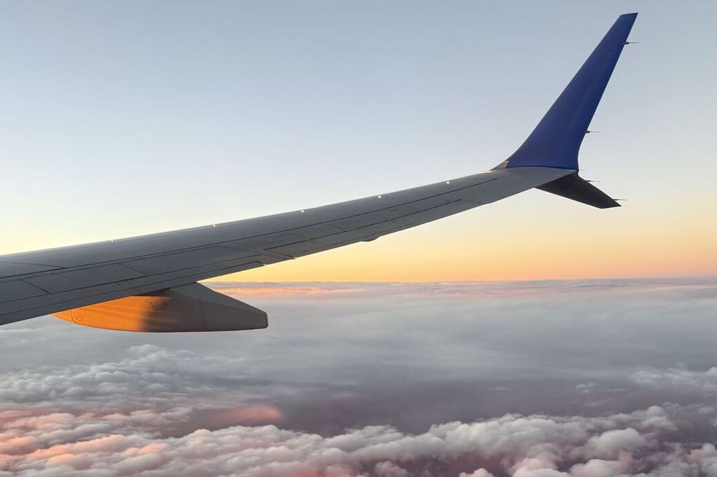 Airplane wing above clouds at sunset
