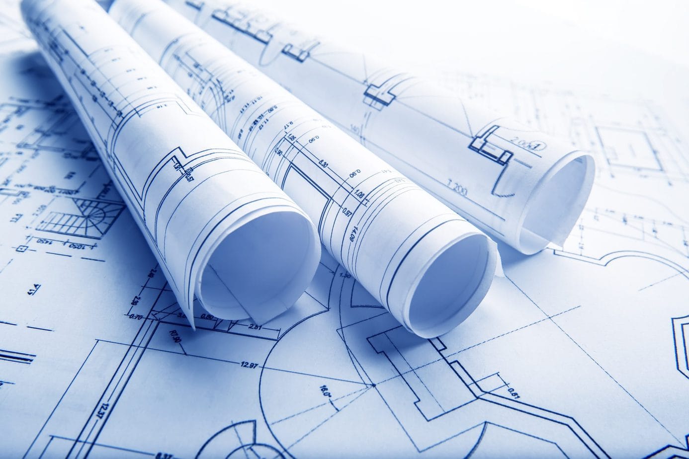 Rolled architectural blueprints resting on construction drawings