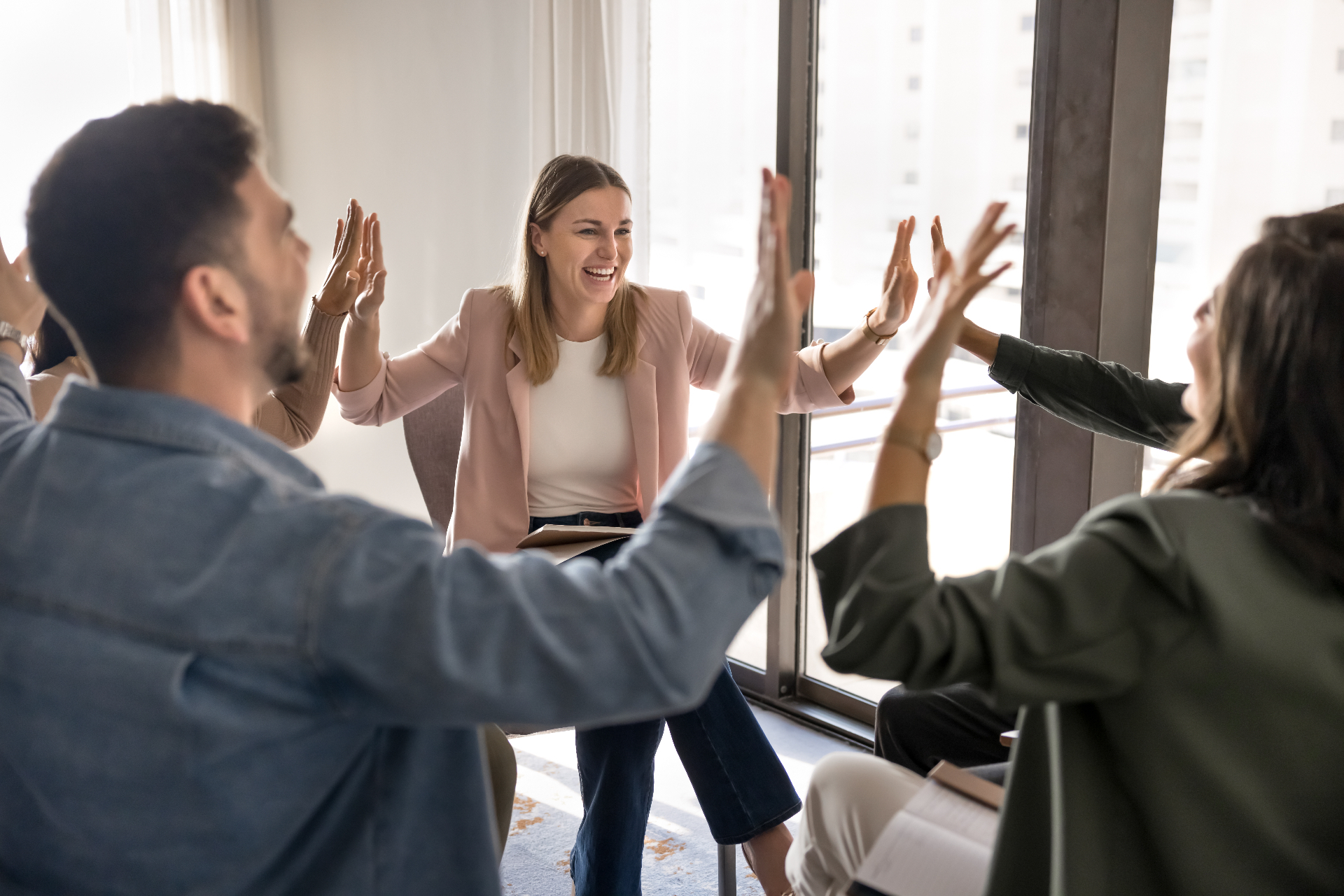 Team of professionals celebrating success with high-fives in a circle, demonstrating Kolbe-aligned collaboration and team chemistry